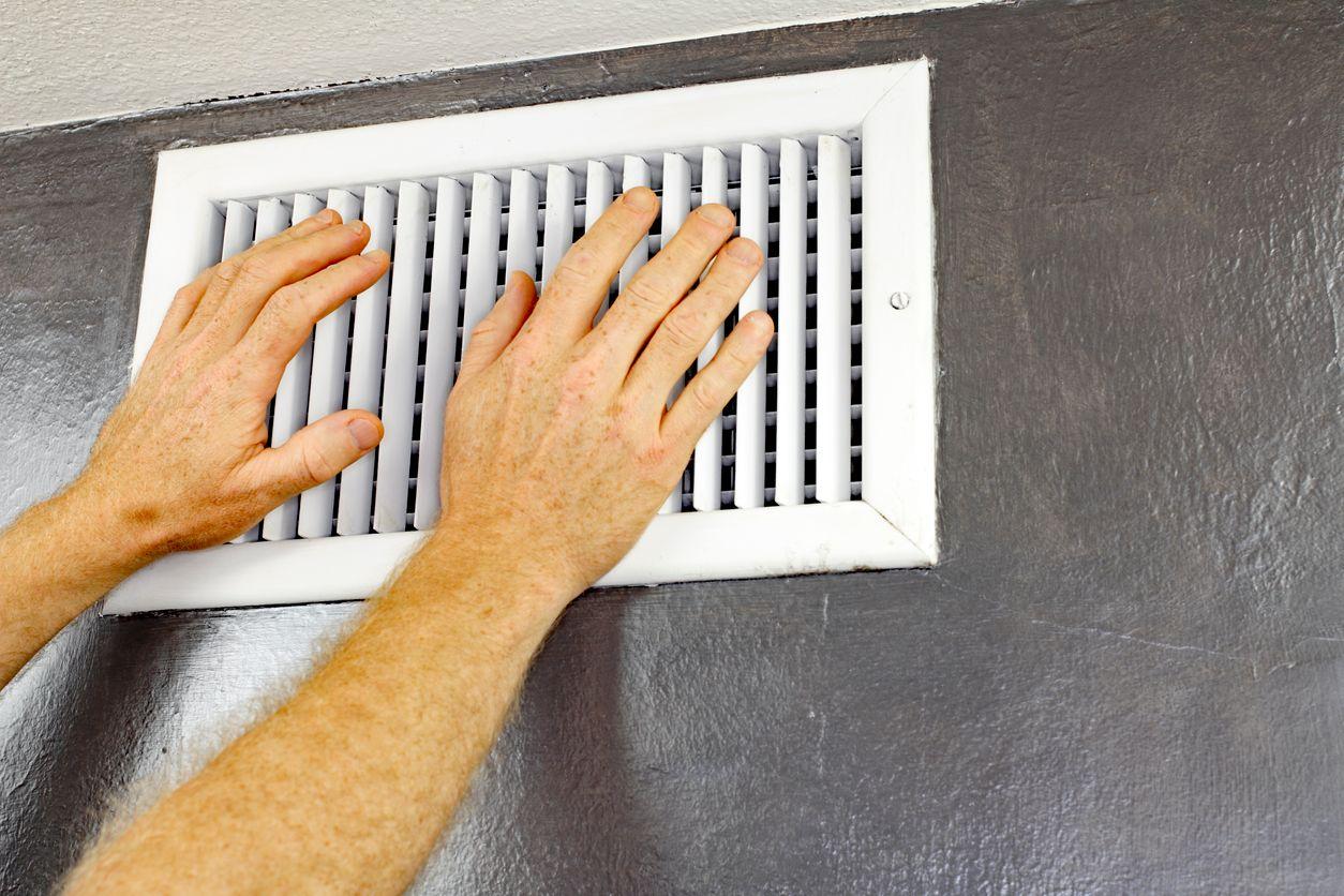 Homeowner putting hands over air vent